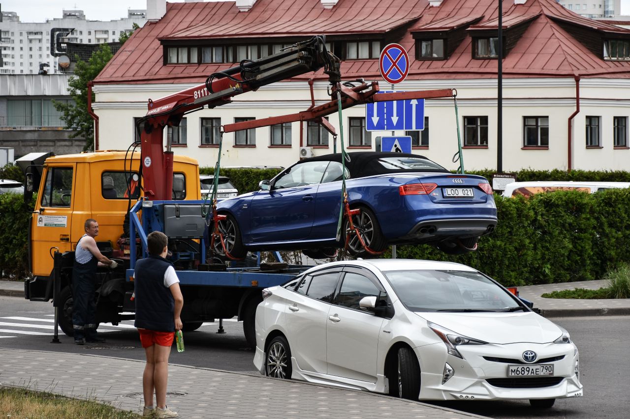 hero-img-02 Towing a blue Audi convertible in a bustling city street.