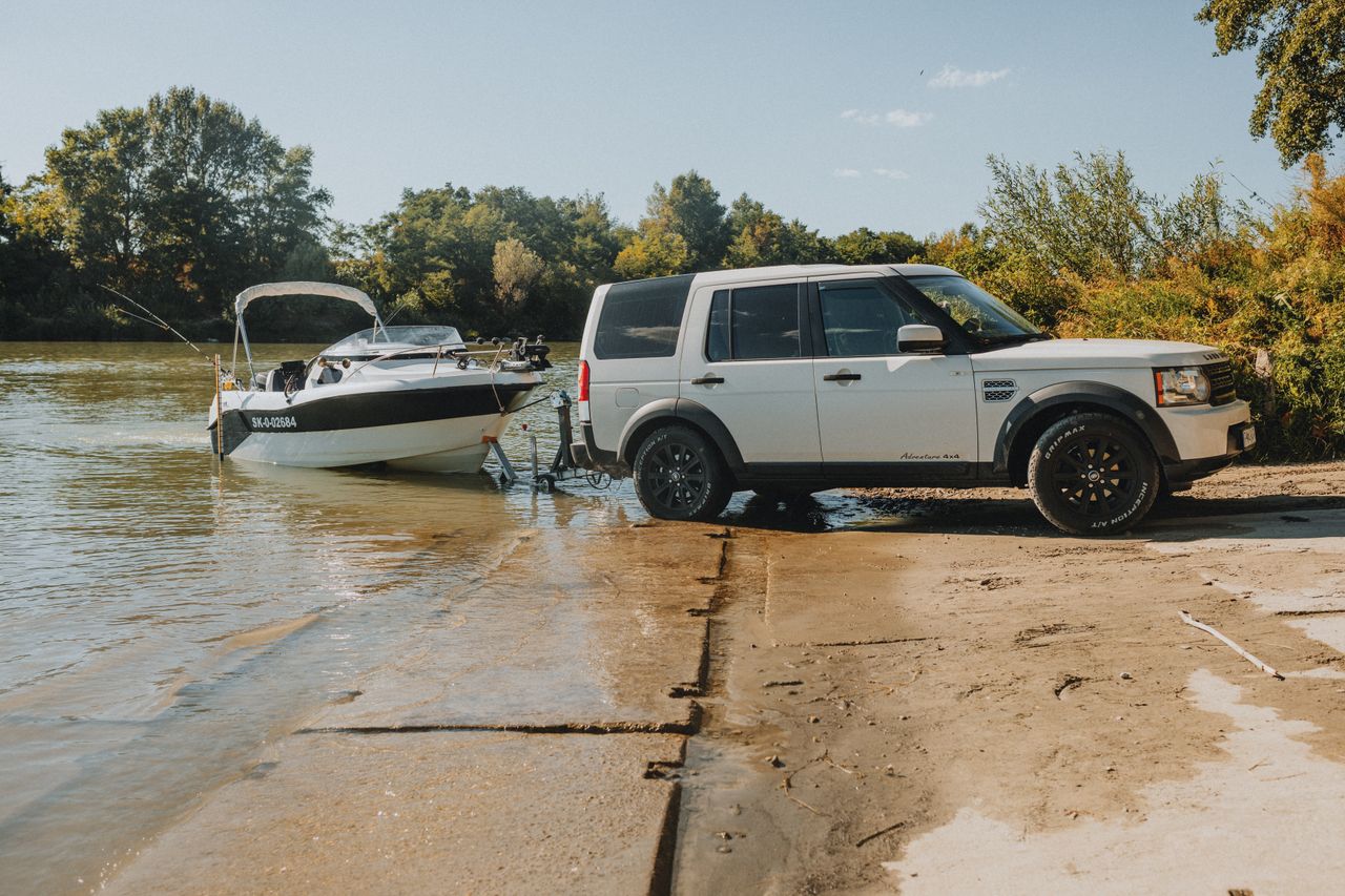 services-01 An SUV launching a speedboat into a river on a sunny day, showcasing outdoor adventure.